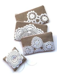 three small purses with white lace on them