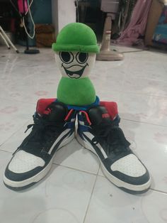 a pair of sneakers with a green hat and glasses on top of each other, sitting on the floor