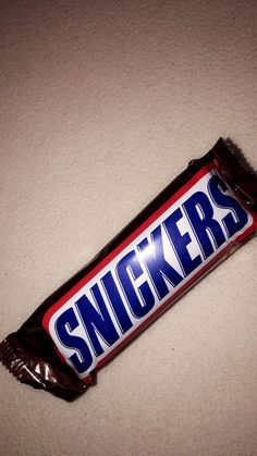 a candy bar with the word snickkers on it sitting on a white surface