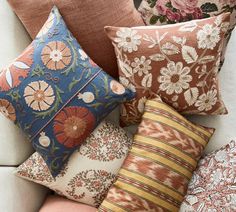 a bunch of pillows sitting on top of a white couch with different colors and patterns