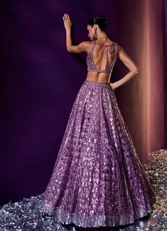 Radiate elegance in this stunning Lavender Sequins Embroidered Bridal Lehenga Set, crafted from luxurious organza fabric. The lavender lehenga is meticulously adorned with tonal and silver sequins, crystals, and bugle beads, creating a mesmerizing interplay of sparkle and sophistication. Paired with a flattering, embellished blouse featuring a modern silhouette, this ensemble exudes contemporary glamour. The look is completed with a matching dupatta bordered with intricate detailing, adding an ethereal charm to this statement piece. Perfect for a bride or bride-to-be, this lehenga set is an exquisite choice for your special day. Composition : Lehenga, Blouse and Dupatta - Organza Care: Dry Clean Only and Vacuum Storage This product can be customized for sleeves, blouse style and colour Del Purple Tissue Silk Sets For Reception, Elegant Purple Tissue Silk Lehenga, Festive Lavender Lehenga With Sheer Dupatta, Purple Lehenga With Zari Work In Tissue Silk, Purple Resham Embroidered Lehenga In Tissue Silk, Silver Embellished Organza Lehenga, Purple Organza Lehenga With Cutdana Detailing, Embellished Silver Organza Lehenga, Fitted Lavender Lehenga With Intricate Embroidery