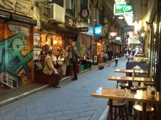 people are sitting at tables in an alleyway