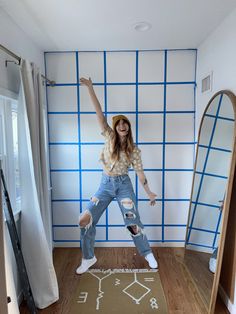 a woman standing on top of a wooden floor in front of a mirror with her arms up