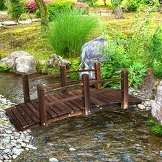 a small wooden bridge over a stream in a garden