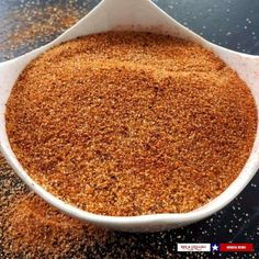 a white bowl filled with brown sugar on top of a black counter next to a spoon