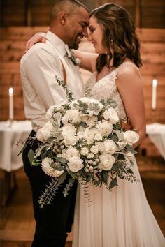 a bride and groom standing next to each other in front of a table with candles