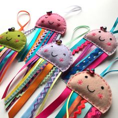 several colorful hair clips with faces on them and ribbons attached to the ends, all decorated in different shapes and sizes