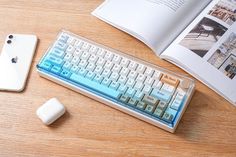 an apple keyboard and mouse on a wooden table next to an open book with pictures