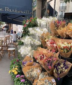 a bunch of flowers that are sitting on the ground in front of some tables and chairs