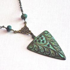 Art Deco Style Necklace - Verdigris Patina Brass Stamping hangs from Ornate Antiqued Brass Connector. The Chain is embellished with small African Turquoise Beads. This necklace also has a tribal look. The pendant is 40mm x 27mm. The design is only on the front side and has a hollow back. Antiqued Brass Chain The patina may vary slightly on the necklace you will receive. This is a stock photo. This particular necklace has been sold. Bohemian Triangle-shaped Jewelry For Festivals, Handmade Bohemian Triangle Jewelry, Handmade Triangle Bohemian Jewelry, Artistic Handmade Green Necklace, Artistic Green Handmade Necklace, Bohemian Jewelry With Patina As A Gift, Unique Green Patina Necklaces, Turquoise Triangle Jewelry Gift, Turquoise Triangle Jewelry For Gifts