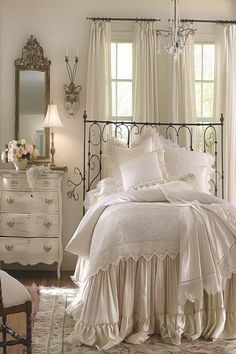 a bedroom with white bedding and chandelier