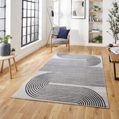 a living room with wooden floors and white walls, an area rug on the floor