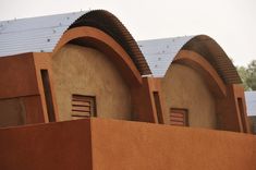 two adobe style buildings with arched windows on the roof