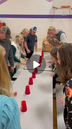 a group of people standing around a table with red cups on it and one person pointing at them