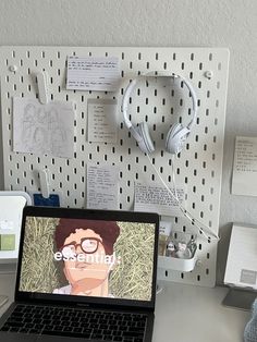 an open laptop computer sitting on top of a desk next to headphones and ear buds