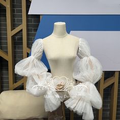 a mannequin with white tulle on display in front of a brick wall