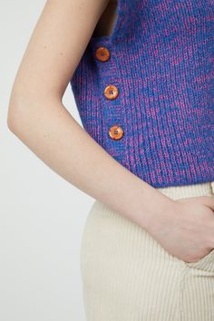 a woman wearing a blue and pink sweater with buttons