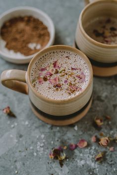 two mugs filled with hot chocolate and rose petale sprinkled on the side