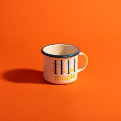 an orange and white mug with the word maple printed on it's side, sitting in front of an orange background