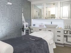 a spa room with white furniture and gray wallpaper, including a large mirror on the wall