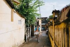 a person riding a bike down a narrow alley way with buildings in the back ground