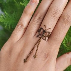 a woman's hand with a ring on it that has a flower and beads attached to it