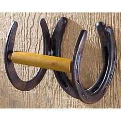 a pair of horseshoes hanging on a wooden wall with a yellow stick sticking out of it