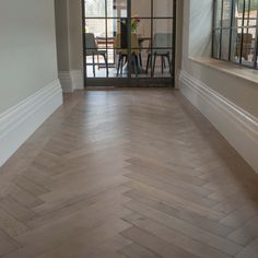 an empty room with wood flooring and glass door leading into the dining room area