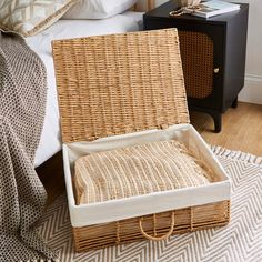 an open wicker basket sitting on top of a bed