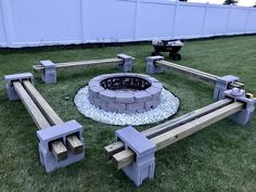 an outdoor fire pit surrounded by benches in the grass