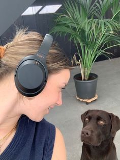 a woman wearing headphones next to a brown dog