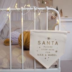 a white crib with christmas lights on it and a santa sign hanging from the top