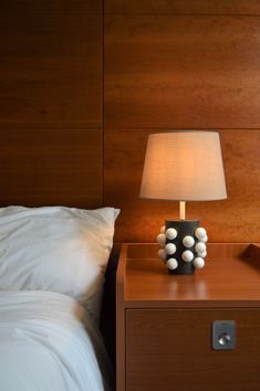 a nightstand with a lamp on it next to a bed