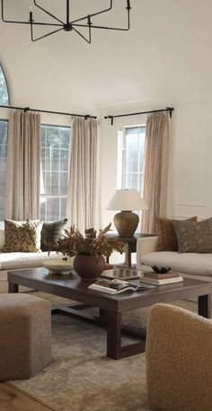 a living room with two couches, chairs and a coffee table in front of windows