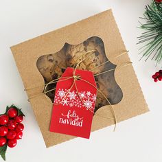 a cookie in a gift box with a red tag on it next to christmas decorations