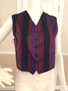 Luxurious silk vest to layer over a blouse to create the Gigli iconic layered romantic look. The jewel tones blend with other Gigli pieces so well. Bronze, purple, burgundy, and black stripes allow it to mix with a variety of colors. The back of the vest is a bronze color. Working pockets on the front of the V notched front of the vest. Five black marbled flat button front closure Made in ItalyFully lined in bronze rayon.Measurements:Length - 21”Bust - 35”Waist - 32” Silk Fitted Vest For Formal Occasions, Formal Fitted Silk Vest, Formal Silk Fitted Vest, Fitted Silk Vest For Workwear, Fitted Silk Vest For Work, Chic Fitted Striped Vest, Purple Sleeveless Vest For Fall, Elegant Striped Vest For Spring, Fitted Silk Chic Vest