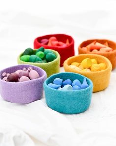 four bowls filled with different colored candies on top of a white tablecloth,