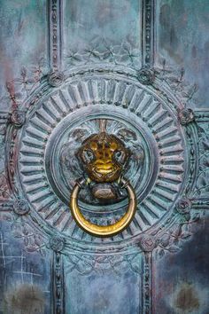 an ornate door handle with a gold ring on it's center and the face of a lion