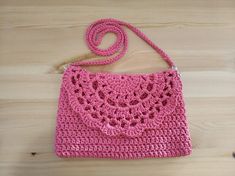 a pink crocheted purse sitting on top of a wooden table