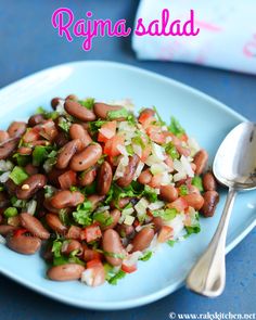 a blue plate topped with beans and veggies next to a spoon on a table