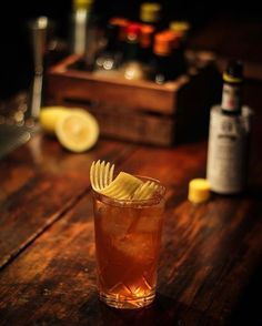 a wooden table topped with a tall glass filled with ice and chips