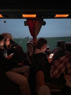 people sitting in the back of a bus looking at their cell phones and taking pictures