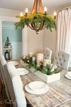 a dining room table with candles on it and christmas decorations hanging from the chandelier