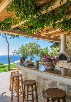 an outdoor bar with several stools and potted plants on the counter next to it