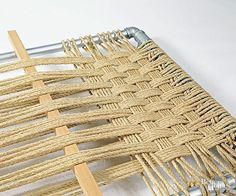 a close up of a woven piece of cloth on a metal frame with wood pins