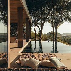 an outdoor area with a pool and pillows on the floor next to it, surrounded by trees