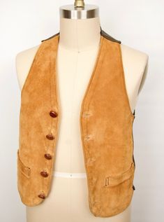 "\"The Thoroughbred\" vintage suede vest with highest level craftsmanship and leather quality you can feel. While we can't be certain whether it's calf skin, cowhide or pig skin without a label, the softness, suppleness, and thickness are evident immediately--as is the workmanship when you turn the piece inside out and see that the suede front is lined with a second layer of smooth leather with each of the leather buttons hand knotted in back (pictured 5th). Also features a rich tan or camel col Classic Brown Leather Vest, Knots In Back, Retro Brown Cotton Vest, Fitted Vintage Leather Vest, Leather Vest With Button Closure, Brown V-neck Vest With Buttons, Vintage Fitted Leather Vest, Leather Sleeveless Vest With Button Closure, Vintage Brown Vest With Button Closure