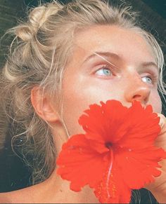 a woman holding a flower up to her face