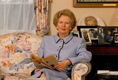 an older woman sitting in a chair reading a newspaper