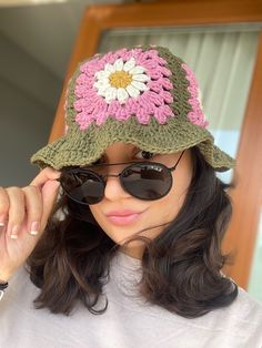 a woman wearing sunglasses and a crocheted hat with a flower on the side